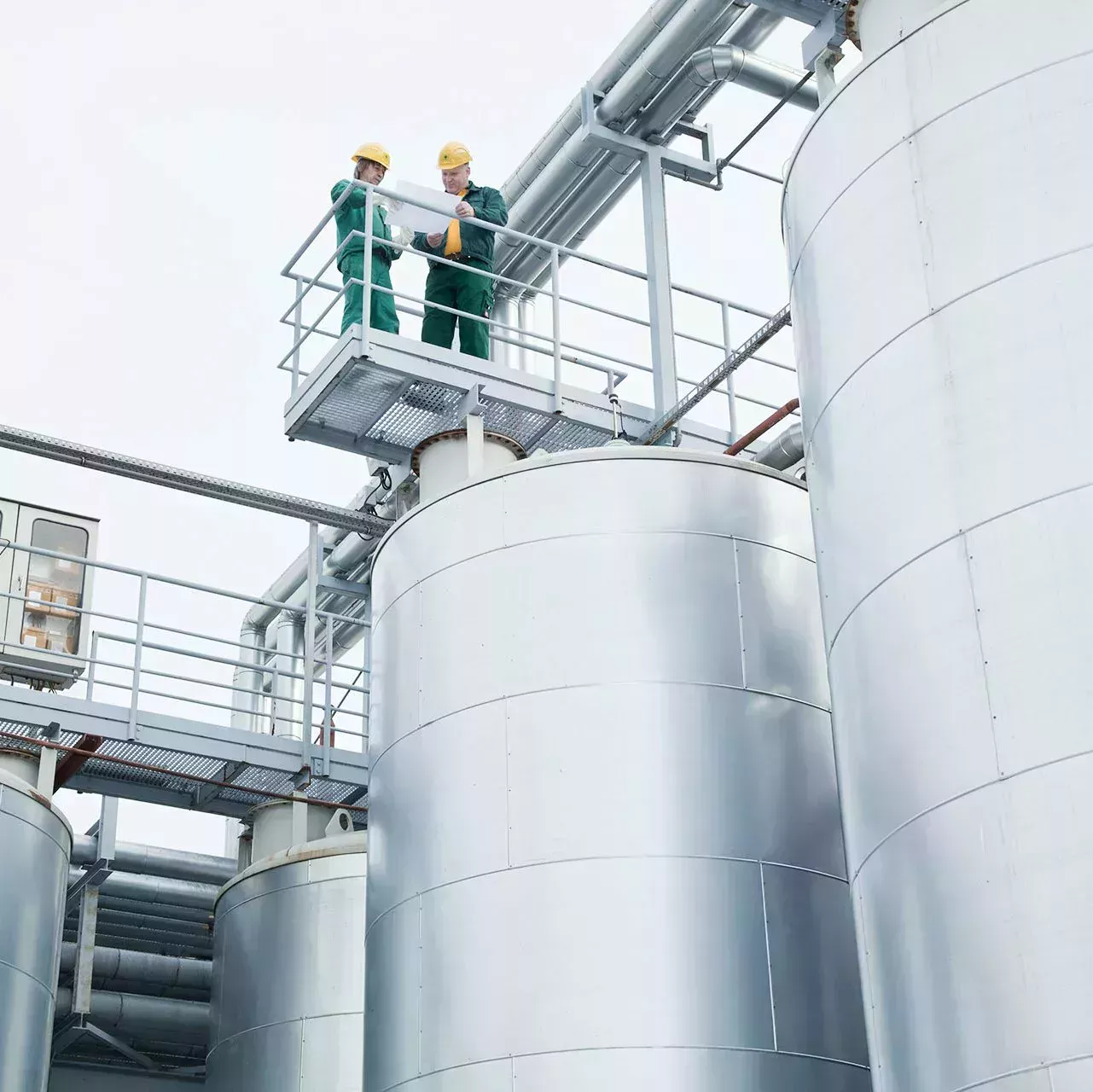 Two employees stand on the oil tanks