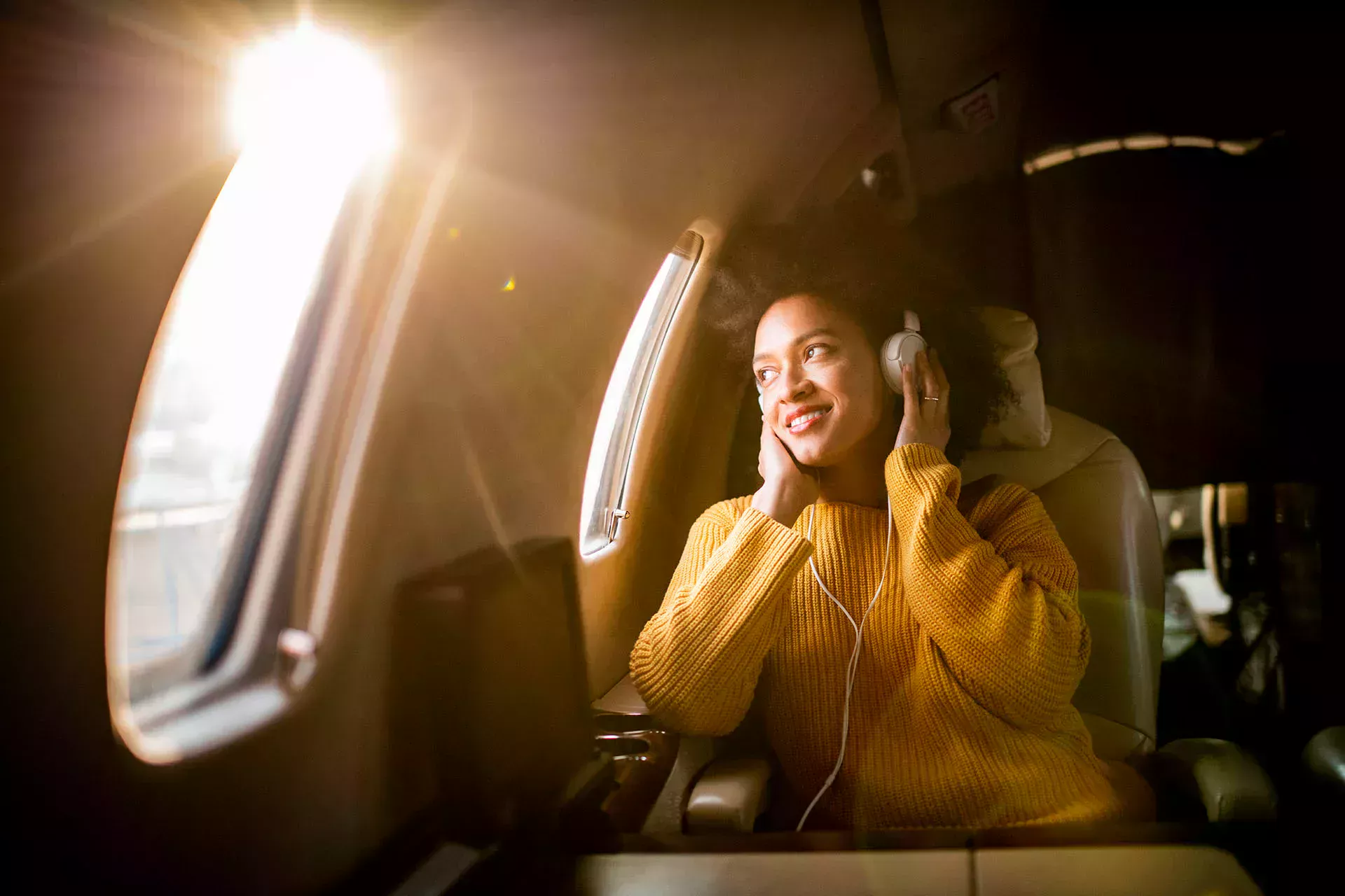 Woman sitting in an aeroplane and listening to music through headphones