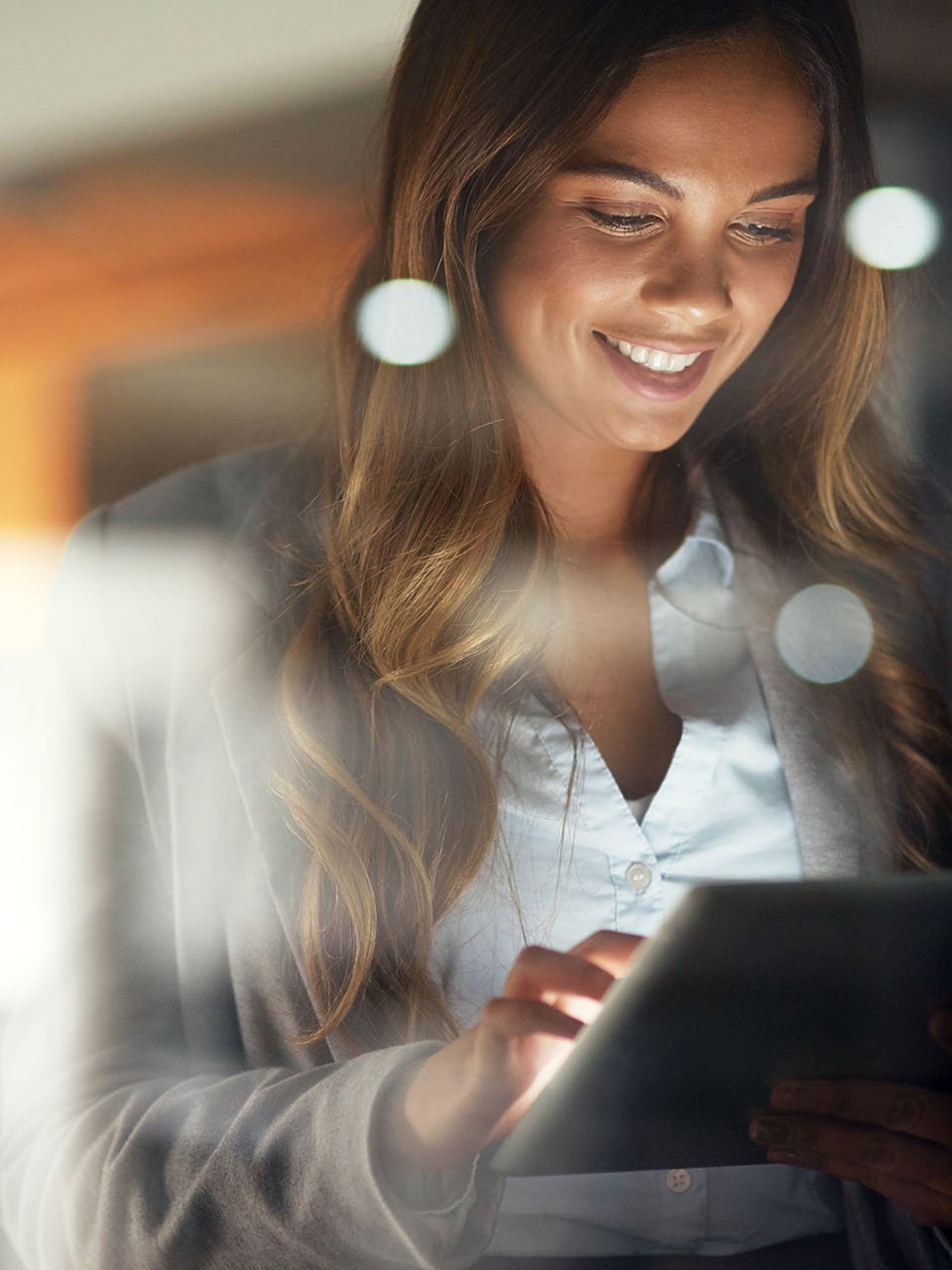 A smiling woman looks at a tablet