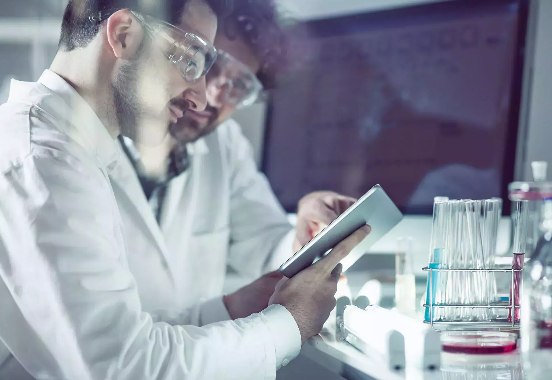 Two chemical technicians are in the lab looking at a tablet