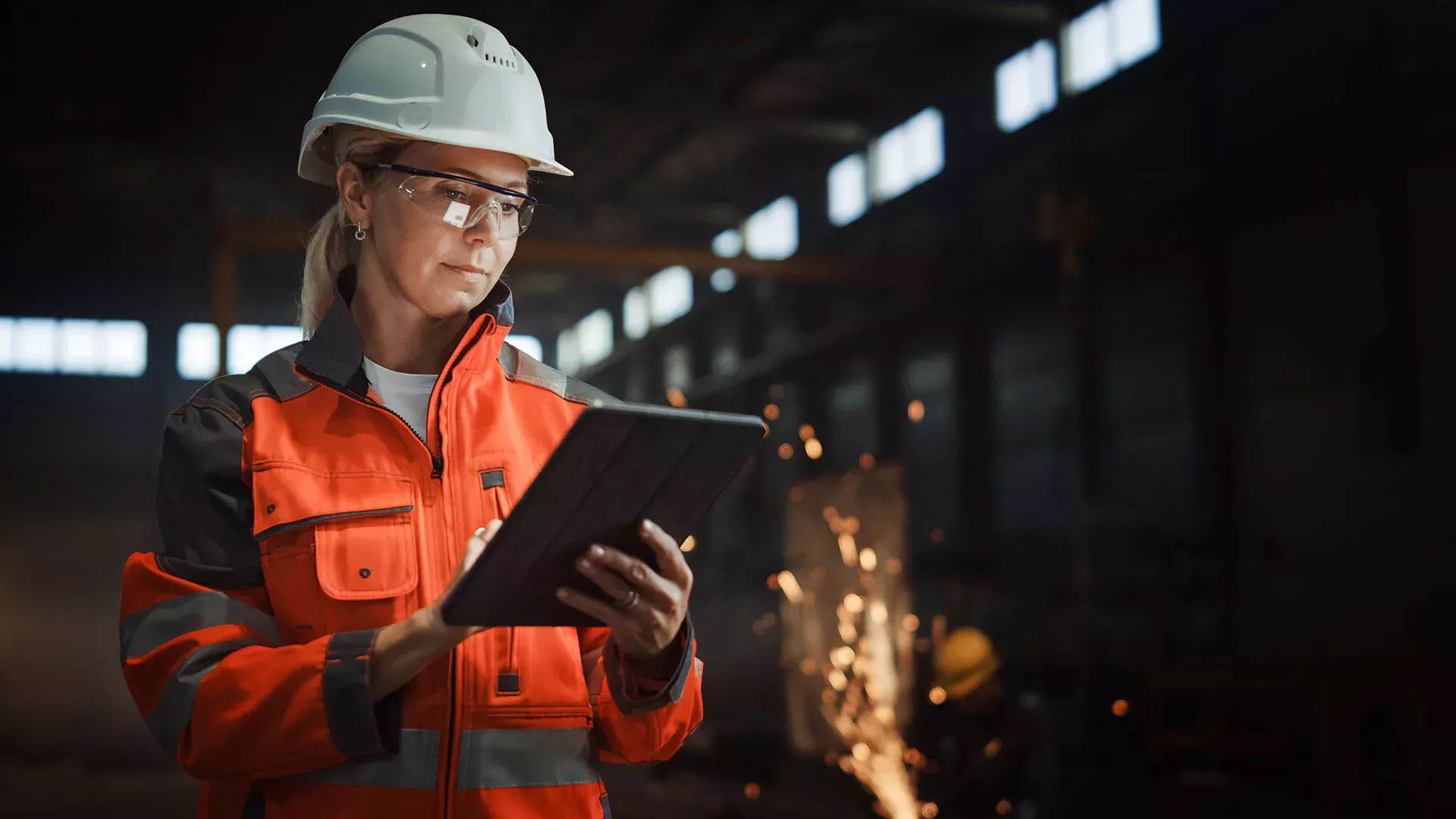 Woman in safety clothing checking things in a steelworks